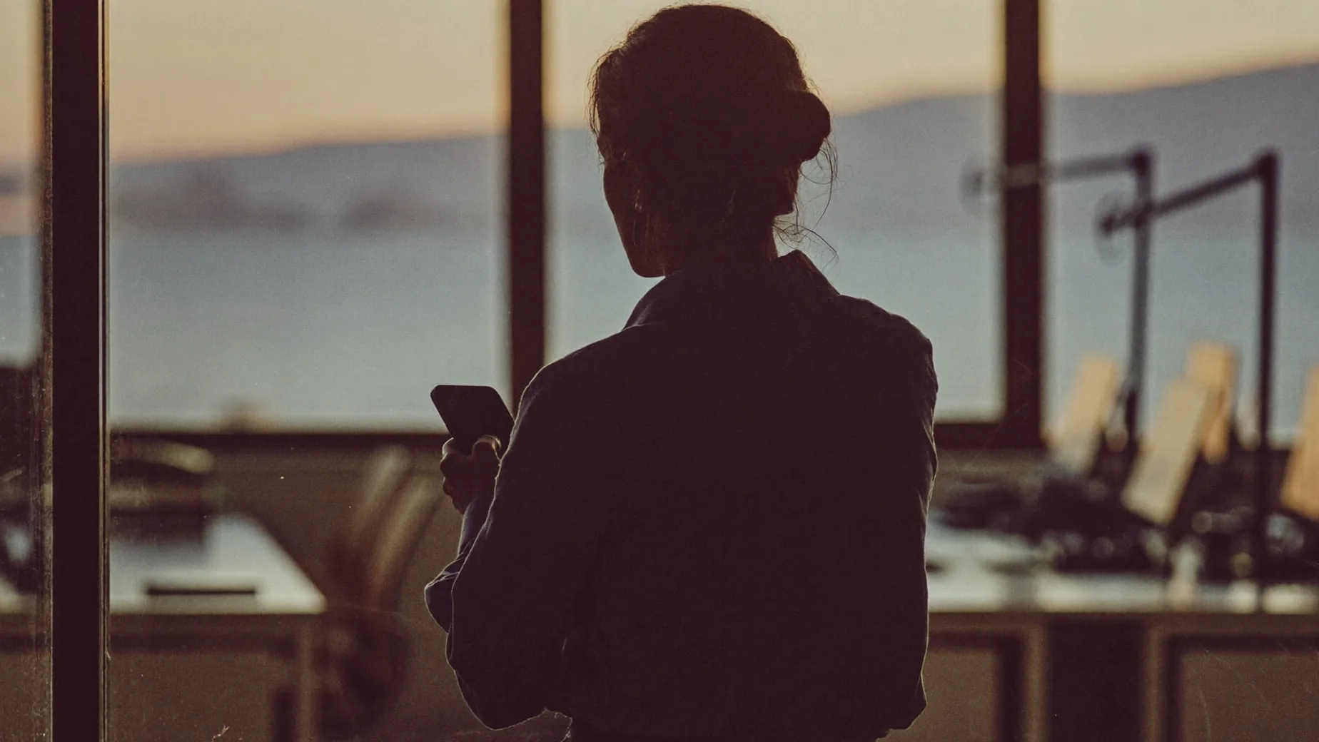 Ufficio di una PMI italiana: un monitor mostra il pannello Campaign Manager di LinkedIn con la stima di audience, accanto un blocco per appunti con calcoli a penna e una tazza di caffè.